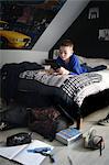 A 10 years old boy playing with his game console in his bedroom