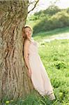 Young woman standing beside an old tree trunk in spring, Germany