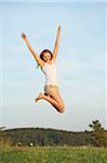 Young woman jumping in the air on a meadow in spring, Germany