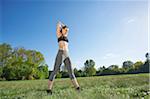 Young woman exercising, stretching in a park in spring, Bavaria, Germany