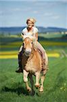 Young woman riding a Haflinger horse in spring, Bavaria, Germany