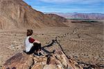 Young woman looking out at view from rocks, Anza-Borrego Desert State Park, California, USA