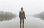 Young woman with camera standing in misty lake