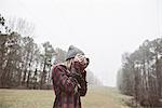 Young woman photographing in misty field
