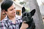 Portrait of young man carrying dog