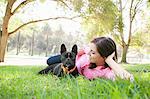 Portrait of young woman and dog lying in park together