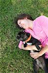 Overhead view of young woman lying in park playing with dog