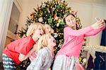 Teenage girl and brothers taking smartphone selfie at christmas
