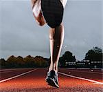 Legs of young female athlete running on race track