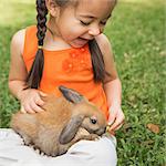 A child with a brown rabbit on her lap.