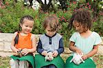 Three children seated in a row, each with a small animal on their lap.