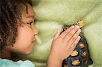 A young girl looking closely at a tortoise.