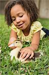 A girl petting a small duckling.