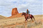 Cowboy Riding Horse with Castel Rock in the background, Shell, Wyoming, USA