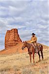 Cowboy Riding Horse with Castel Rock in the background, Shell, Wyoming, USA
