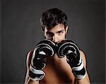 Studio portrait of young man with boxing gloves in front of face