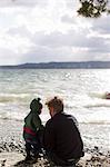 Father and baby daughter crouching on lakeside, Lake Starnberg, Bavaria, Germany