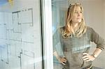 Architect looking at plans taped to glass wall