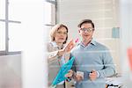 Businessman and woman pointing at office glass wall