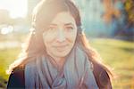 Portrait of mid adult woman listening to headphones in park