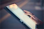 Hand of woman using digital tablet touchscreen at dusk