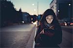 Mid adult woman using digital tablet on street at dusk