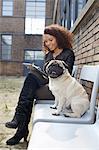 Portrait of pug dog sitting on chair with young woman in office courtyard