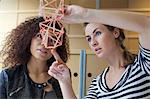 Two young female designers looking at handmade model in creative office