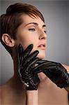 Studio portrait of woman with hand on her cheek wearing black leather gloves