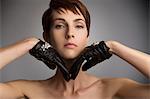 Studio portrait of woman with hands on chin wearing black leather gloves