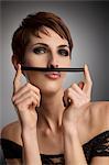 Studio portrait of woman holding up licorice stick as mustache