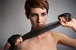 Studio portrait of woman pulling black silk scarf around hands