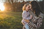 Portrait of young woman carrying daughter in field