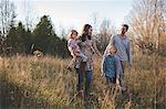 Young couple with son and daughter strolling in field