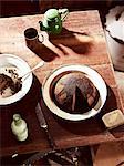 Rustic table with dish of steamed treacle pudding and teapot