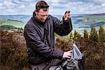 Male hiker tying rucksack on heather moors, Pateley Bridge, Nidderdale, Yorkshire Dales