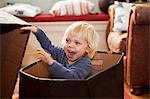 Boy hiding in cardboard box in living room