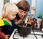 Mother and son waiting for porridge to cook in kitchen