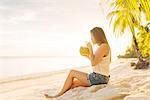 Young woman drinking fresh coconut milk on Anda beach, Bohol Province, Philippines