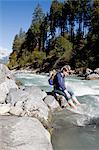 Male hiker sitting on rock with bare feet in river, Lauterbrunnen, Grindelwald, Switzerland