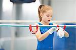 Young gymnast using training wrist straps to aid practise on bars