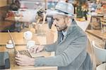 Businessman sitting in front of cafe window using laptop