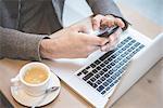 Cropped shot of businessman sitting in cafe texting on smartphone