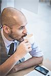 High angle view of businessman sitting in cafe drinking coffee