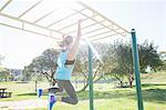 Woman training in park on monkey bars