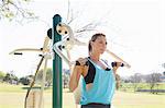 Mid adult woman in park training on weight machine