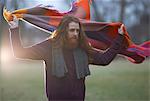 Man wrapping blanket around himself in countryside