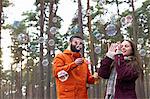 Young couple blowing bubbles in forest