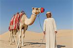 Portrait of bedouin with camel in desert, Dubai, United Arab Emirates