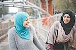 Two young female friends laughing on park path